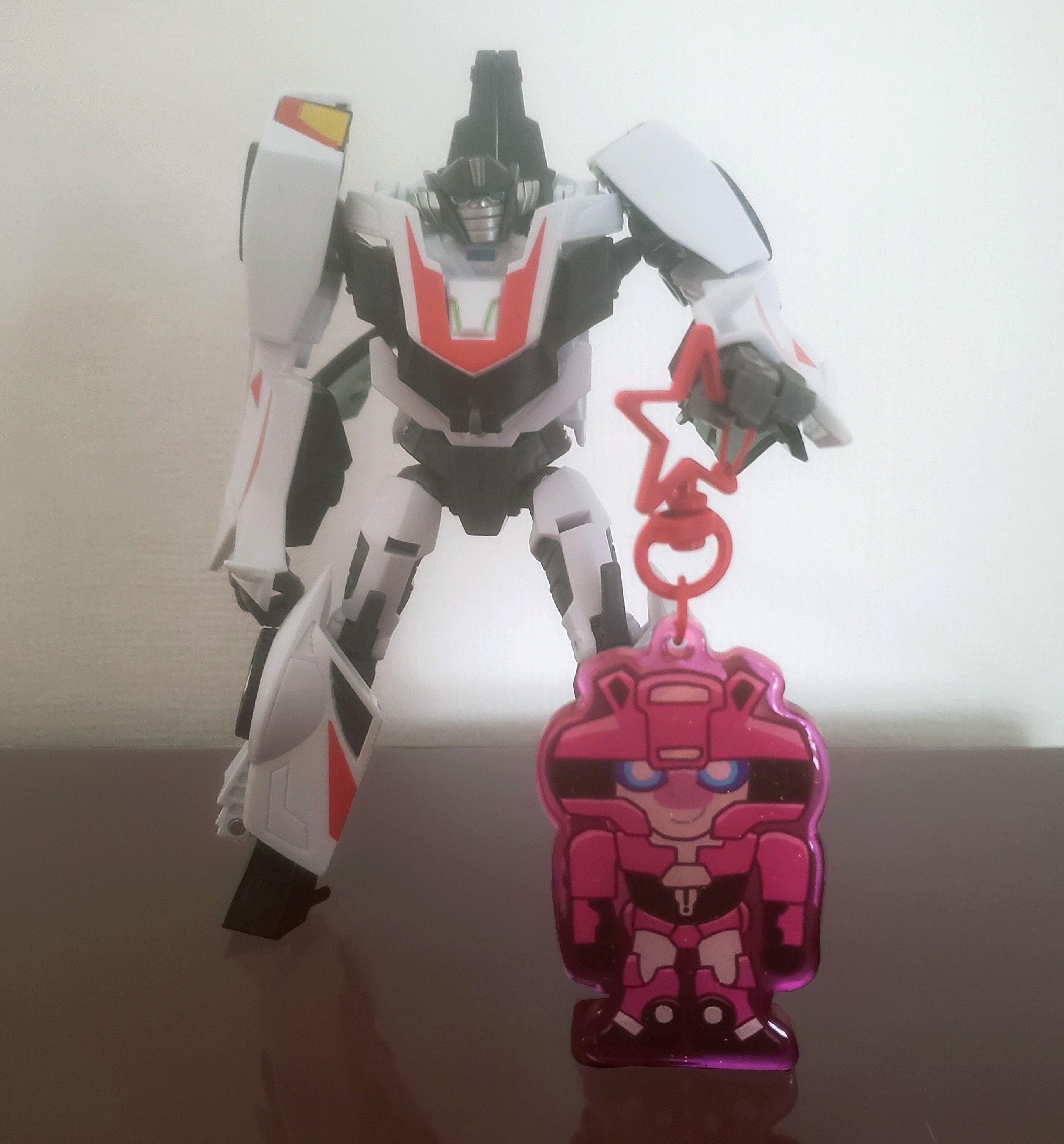 A Wheeljack toy holding a keychain of Elita-1.